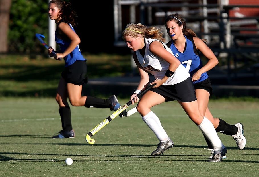 Energetic field hockey game with women players competing outdoors.